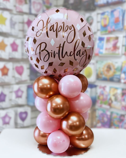 Balloon arrangement with a 'Happy Birthday' balloon on a stand against a colorful background. Balloon delivery and pickup in Nesconset or Miller Place, NY.